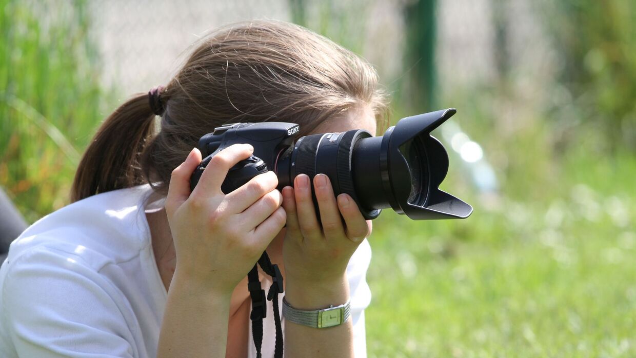 Fotografin bei einer Fotoaufnahme mit einer Spiegelreflexkamera 